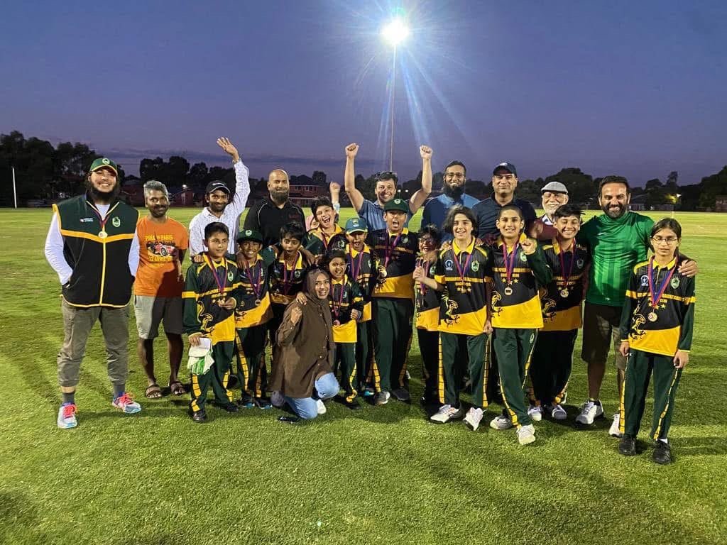 RPBCC junior players, coaches and families celebrating with medals on the ground at dusk